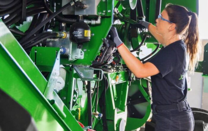 Nainen korjaamassa traktoria.