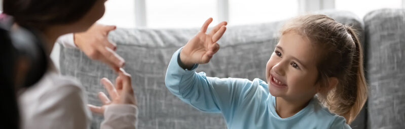 Lapsi viittoo viittomakielellä aikuiselle.