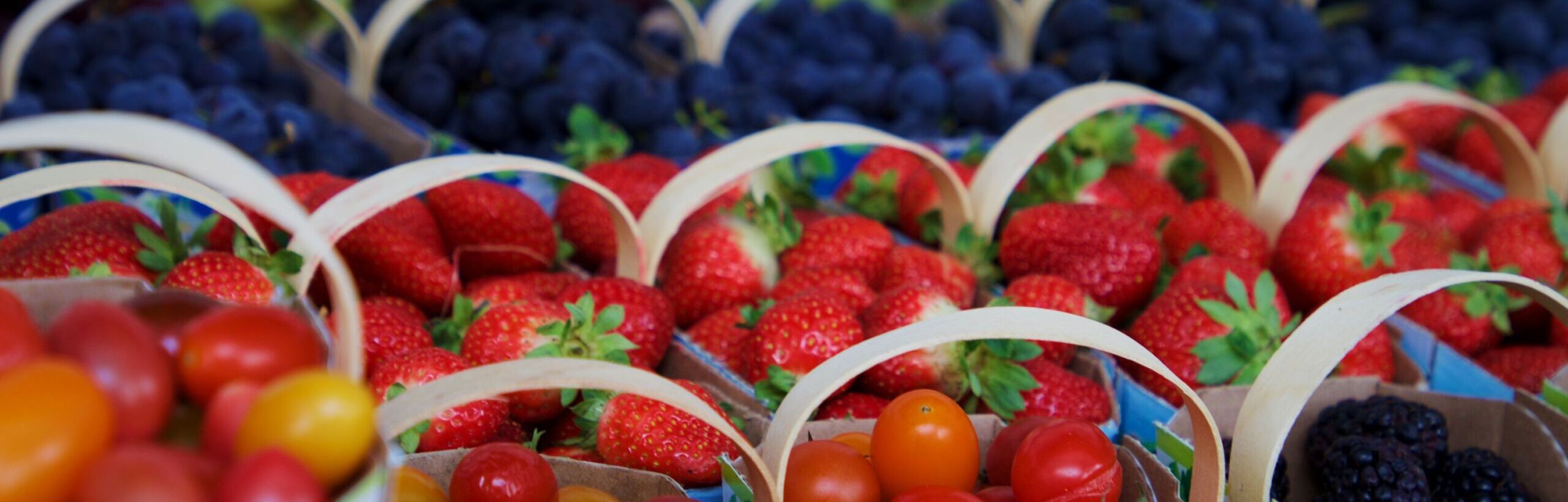 Pienissä astioissa erilaisia marjoja ja vihanneksia kaupan myyntitiskissä.